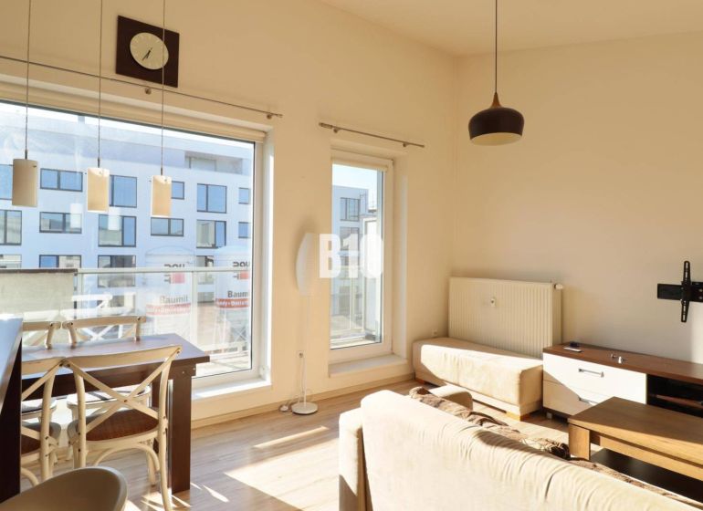 Wohnzimmer in einer 2-Zimmer-Wohnung mit hellen Möbeln und einem Boden in Holzoptik.