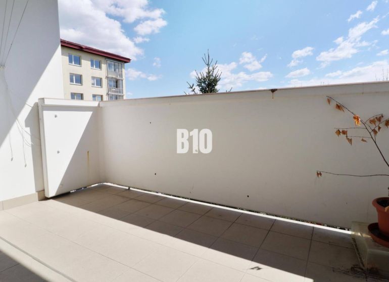 Balkon in einer 3-Zimmer-Wohnung. Pflanze im Blumentopf, Fliesen, teilweise Blick auf das Nachbargebäude.