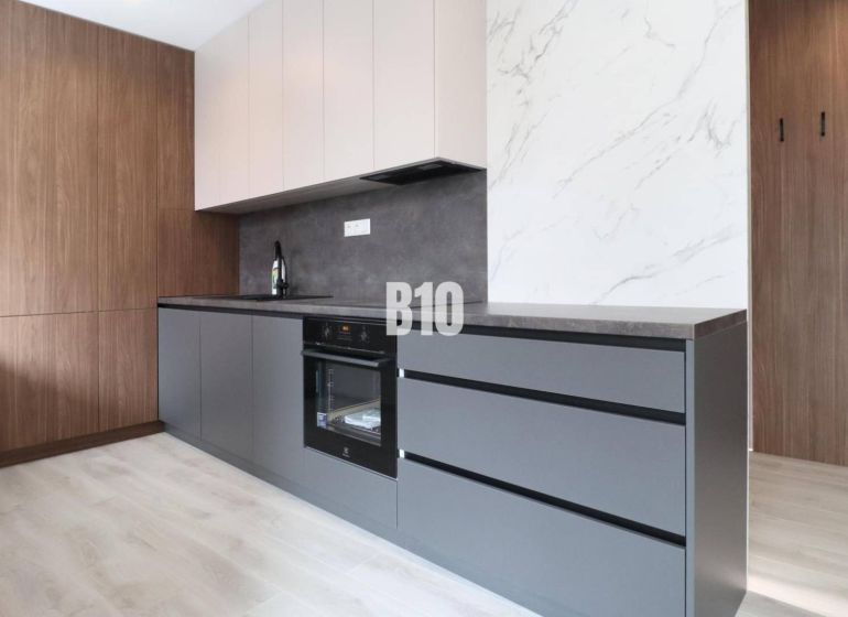 Küche in einer 2-Zimmer-Wohnung mit Holzboden und modernen Schränken.