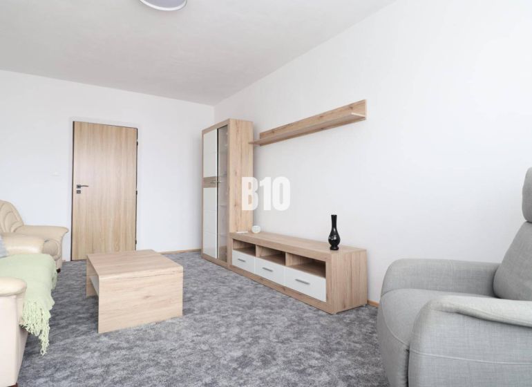 Wohnzimmer mit beigem Sofa, grauem Sessel und Möbeln mit Holzdekor in einer 3-Zimmer-Wohnung.