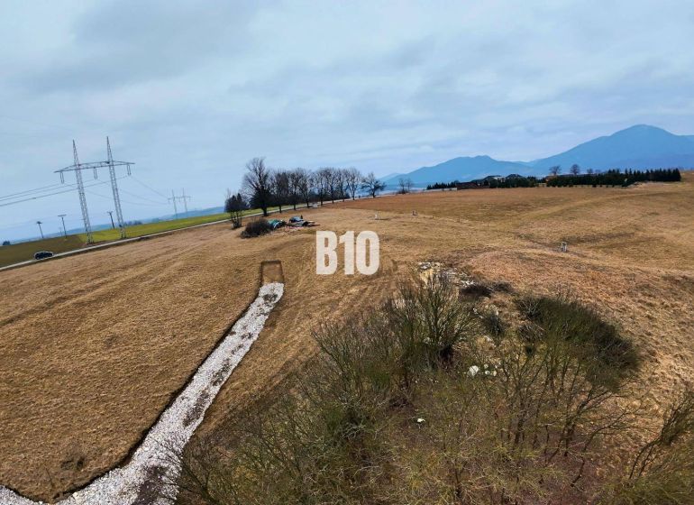 Hügelige Landschaft in Laskári, geeignet für Wohnbaugrundstücke, mit Stromleitungen im Hintergrund.