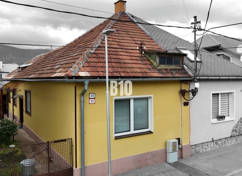 Ein Einfamilienhaus in Martin mit gelber Fassade und schrägem Dach, neben dem Zugangsweg.