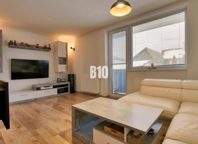 Wohnzimmer in einer 3-Zimmer-Wohnung mit Holzboden und einem bequemen weißen Sofa.