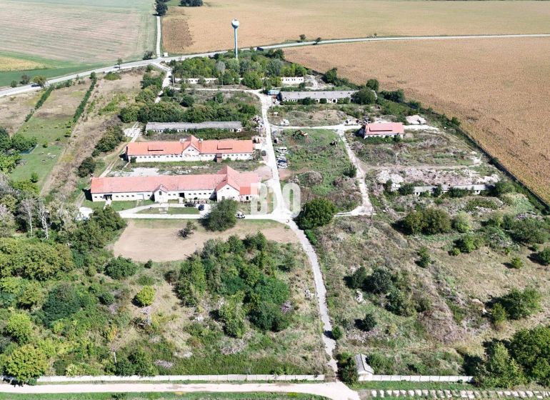 Ein Gelände mit Gebäuden und Natur, umgeben von landwirtschaftlichen und forstwirtschaftlichen Flächen in Levice.