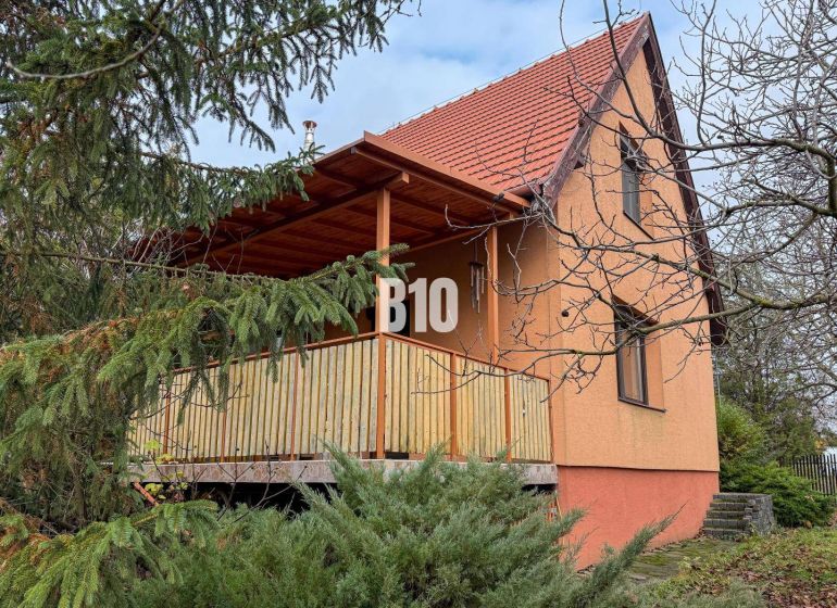 Ein Einfamilienhaus in Vlkas, umgeben von Grün, traditionell mit einem schrägen Dach, einem Holzbalkon.