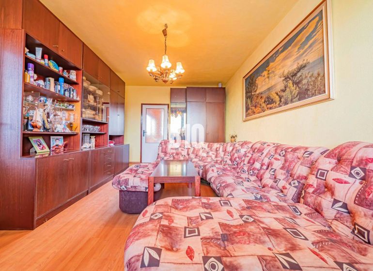 Wohnzimmer in einer 3-Zimmer-Wohnung mit Holzboden und Ecksofa.