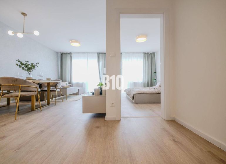 Innenraum einer 2-Zimmer-Wohnung mit Holzboden, Esstisch und Bett.