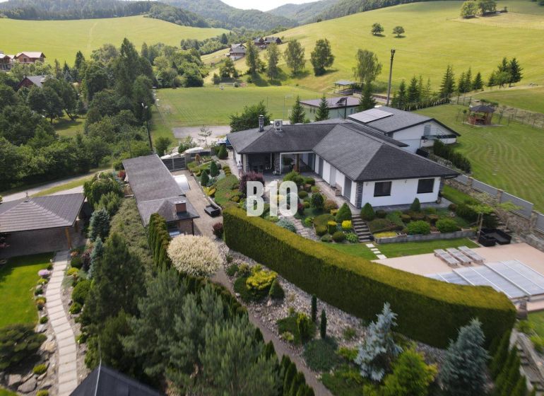 Eine Villa in Súľov-Hradná, umgeben von einem schönen Garten und hügeliger Landschaft.