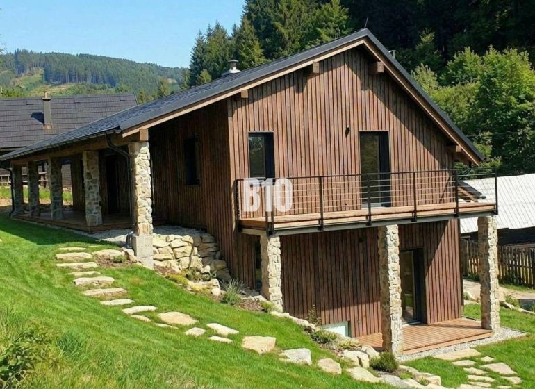 Eine Holzhütte in Horná Mariková, umgeben von Grün und hügeliger Landschaft.