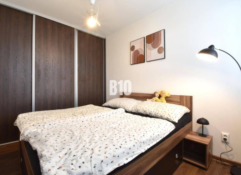 Schlafzimmer in einer 3-Zimmer-Wohnung mit Einbauschrank und Bett mit Holzdekor.