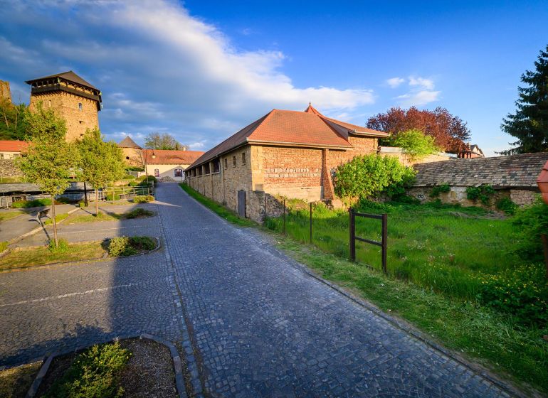 Ein gepflasterter Gehweg entlang eines historischen Gebäudes auf einem Gewerbegrundstück in Fiľakovo.