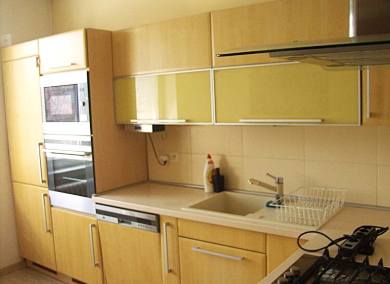 Küche in einer 2-Zimmer-Wohnung mit eingebauten Geräten und einem Boden in Holzoptik.