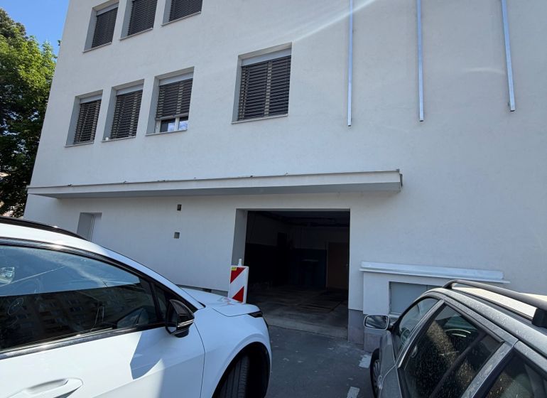 Gebäude mit Garagen in der Langen Straße 3 in Prievidza, geparkte Autos vor dem Gebäude.