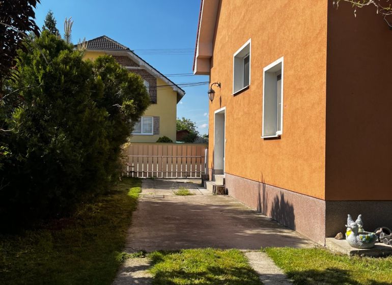 Ein Einfamilienhaus in Čalovec mit einer orangefarbenen Fassade, einem Rasen und einer befestigten Zufahrtsstraße.