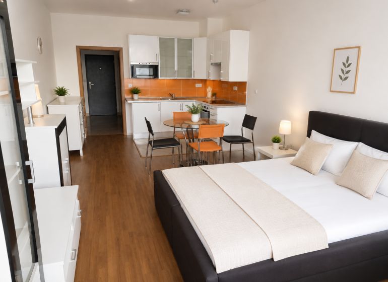 Einzimmerwohnung mit Küchenzeile, Holzboden und einem Bett in neutralen Farben.