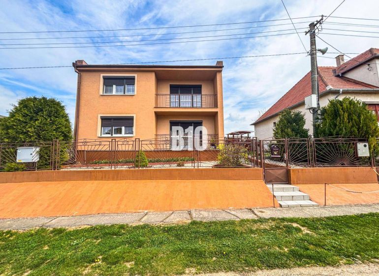 Ein Einfamilienhaus in Lukáčovce mit Garten und erhöhtem Eingang, umgeben von einem Zaun.