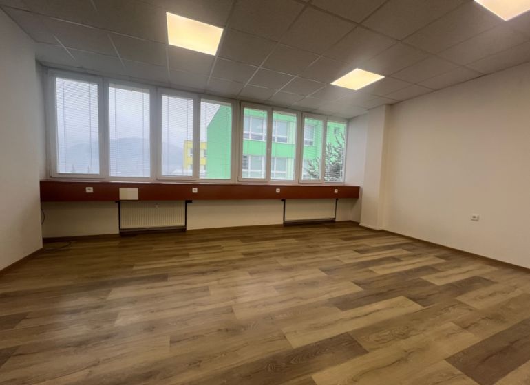 Ein leeres Büro mit einem Holzboden und großen Fenstern.