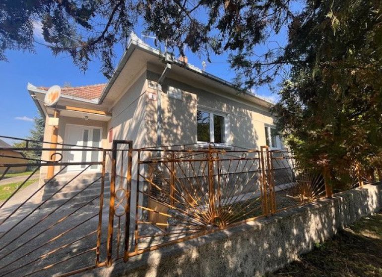Ein Einfamilienhaus in Vrakúňa mit einem dekorativen Metallzaun und Bäumen im Hintergrund.