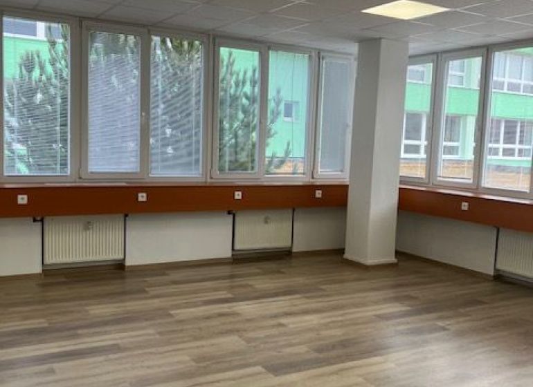 Büros mit Holzboden und großen Fenstern.