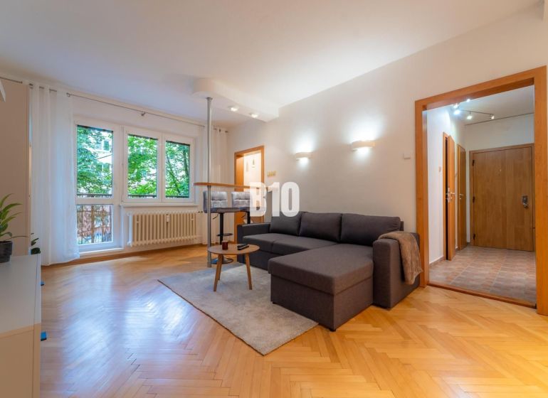 Wohnzimmer in einer Zweizimmerwohnung mit Holzboden und großem Fenster.