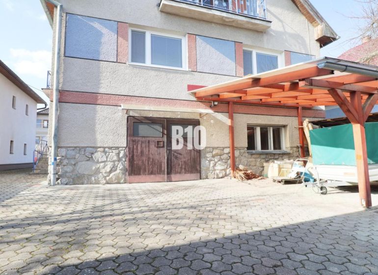 Ein Einfamilienhaus in Turany mit befestigter Zufahrtsfläche und einem Carport.