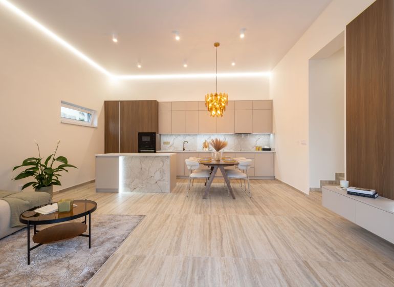 Küche und Wohnzimmer in einem Einfamilienhaus mit dekorativer Leuchte und Boden mit Holzdekor.