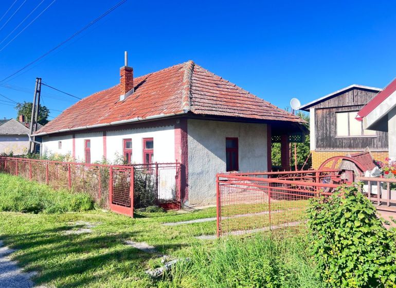 Ein Einfamilienhaus in Žirany, Bezirk Nitra, mit rotem Dach und Zaun.