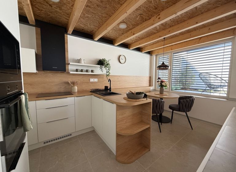 Eine Küche in einem Einfamilienhaus mit Holzboden, Holzbalken und einem Esstisch.