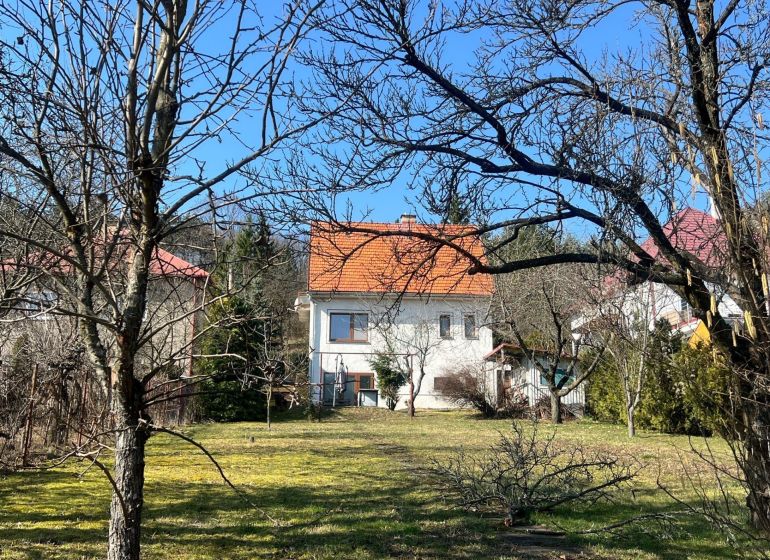Ein Einfamilienhaus in Podhájska, Kráľová, umgeben von Bäumen und Rasen, mit einem orangefarbenen Dach.