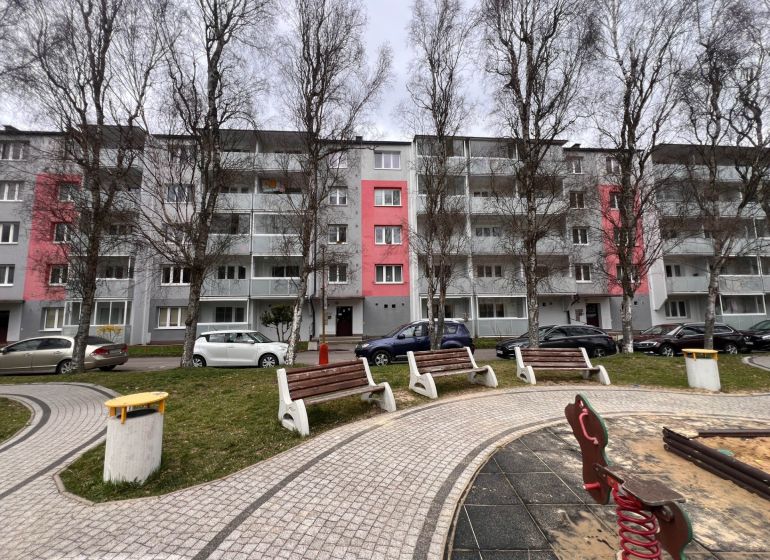 Ein Wohnhaus in Ružomberok mit Bäumen und Parkplätzen vor den Zweizimmerwohnungen.
