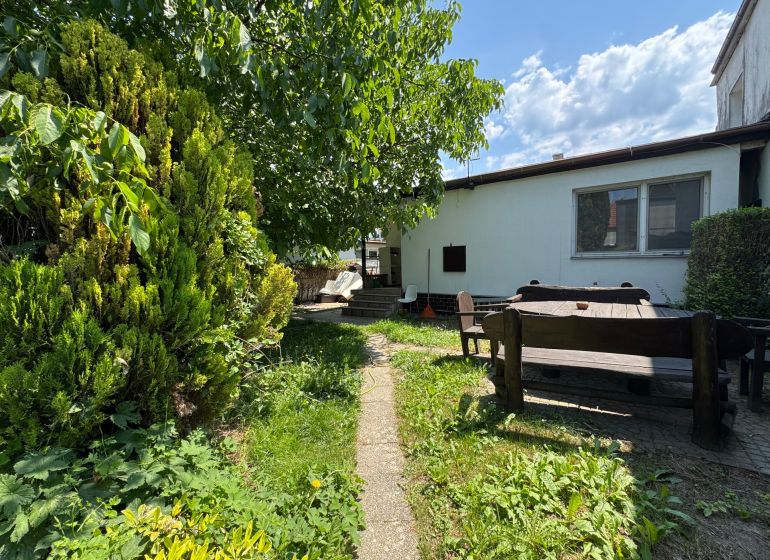 Der Garten eines Einfamilienhauses in Bratislava - Ružinov in der Senná-Straße mit einer Holzsitzgelegenheit.