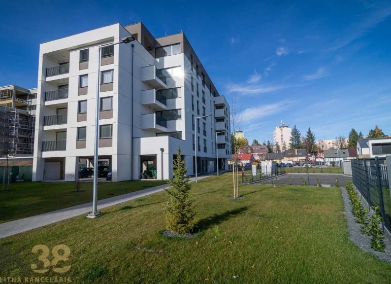 Ein Wohnhaus in Poprad mit grünem Rasen und benachbarten Gebäuden im Hintergrund.