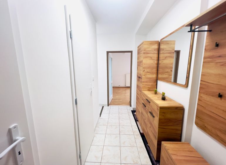Der Flur in einer 2-Zimmer-Wohnung mit Fliesen und Holzmöbeldekor.