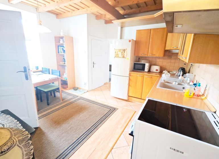 Küche in einer 2-Zimmer-Wohnung mit Holzboden und Holzdecke.