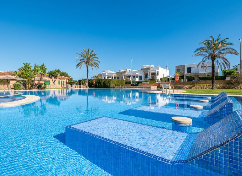 Schwimmbad bei der Ferienwohnung in Cala Murada auf Mallorca mit Palmen und Liegestühlen.