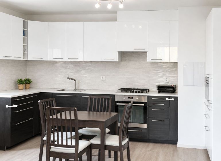 Küche in einer 3-Zimmer-Wohnung mit Esstisch und Boden in Holzoptik.
