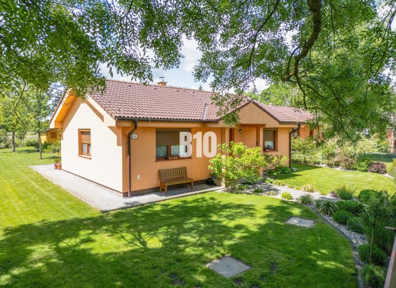 Ein Einfamilienhaus in Bíľkové Humence, umgeben von einem gepflegten Garten und grünem Rasen.