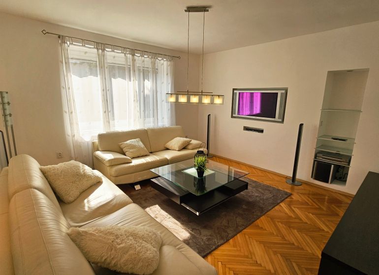 Wohnzimmer mit weißem Sofa und Holzboden in einer 2-Zimmer-Wohnung.