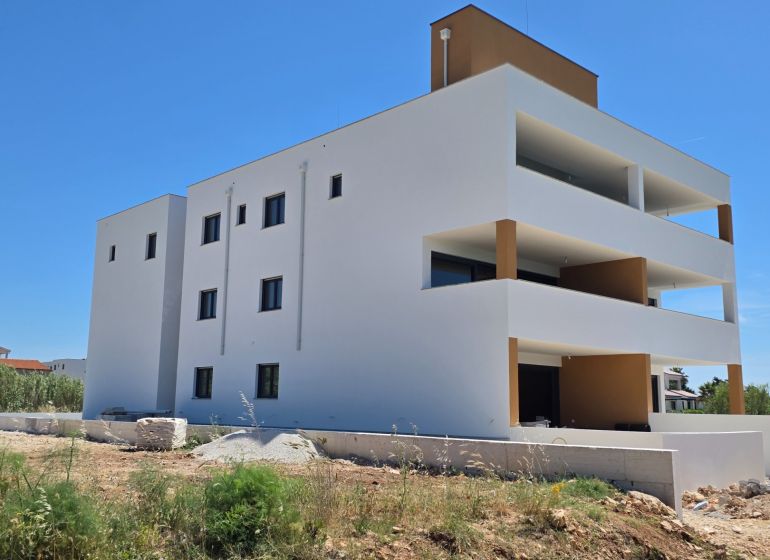 Weißes Wohnhaus mit Balkonen in Privlaka gegenüber dem blauen Himmel, 3-Zimmer-Wohnung.