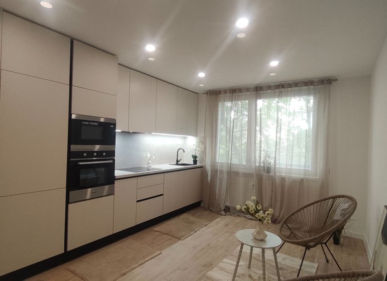 Küche in einer 4-Zimmer-Wohnung mit Holzboden und großem Fenster.