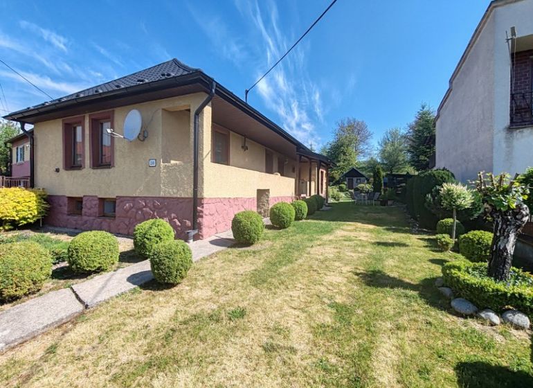 Ein Einfamilienhaus in der Hauptstraße in Banské mit einem gepflegten Garten und einem gepflegten Rasen.
