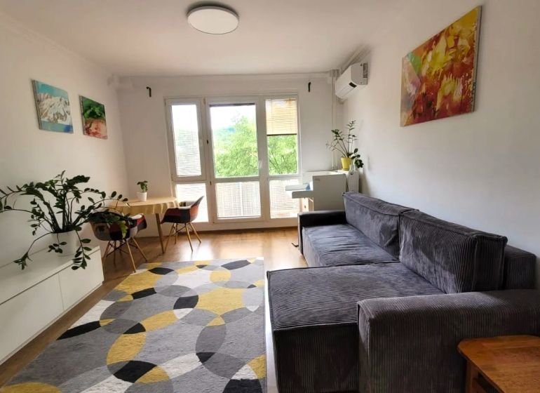 Wohnzimmer mit Sofa in einer 3-Zimmer-Wohnung mit Holzboden und Dekorationen.