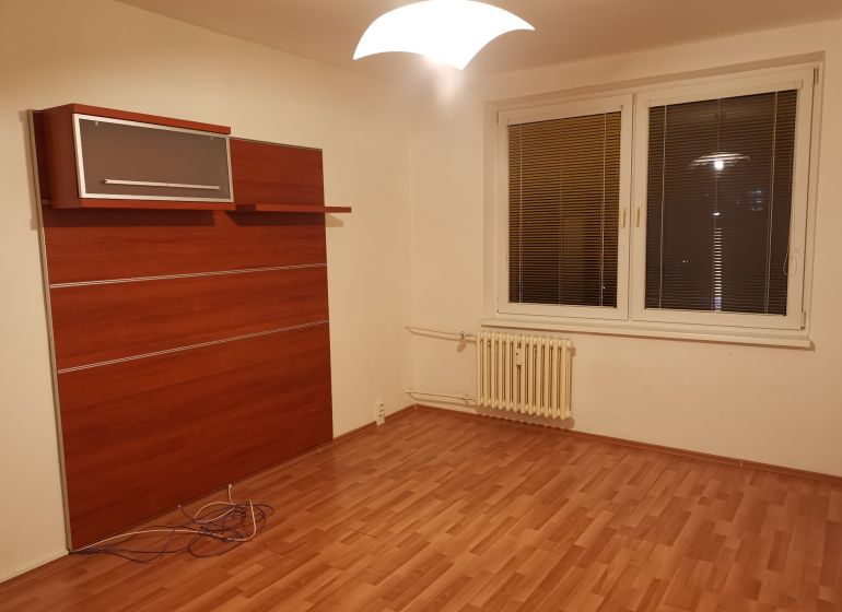 Ein Zimmer mit einem Boden in Holzoptik, weißen Wänden und einem Wandschrank in einer 3-Zimmer-Wohnung.