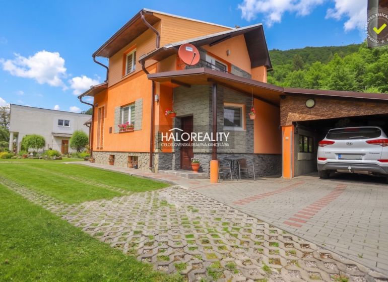 Einfamilienhaus in Dolná Mariková mit Garage, Rasen und Parkfläche vor dem Haus.
