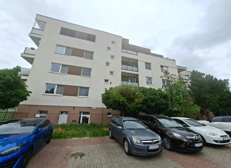 Wohnhaus in der Športová-Straße in Dunajská Lužná mit Parkplatz und Autos vor dem Gebäude.