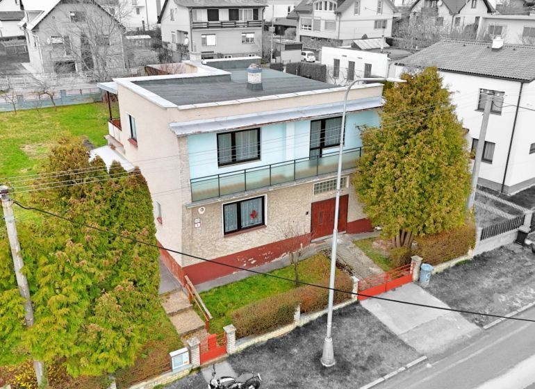 Ein zweistöckiges Einfamilienhaus in Martin mit Garten, umgeben von Bäumen und einem Zaun.