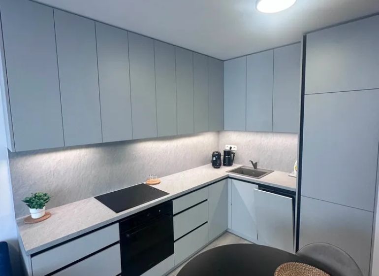 Küche in einer 2-Zimmer-Wohnung mit Holzboden und grauen Schränken.