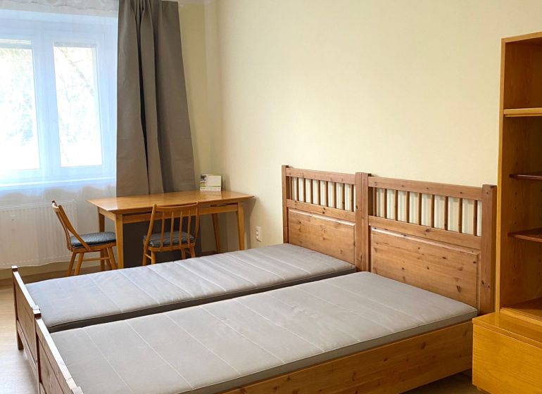 Schlafzimmer mit Holzbett, Tisch und Boden mit Holzdekor in einer 3-Zimmer-Wohnung.