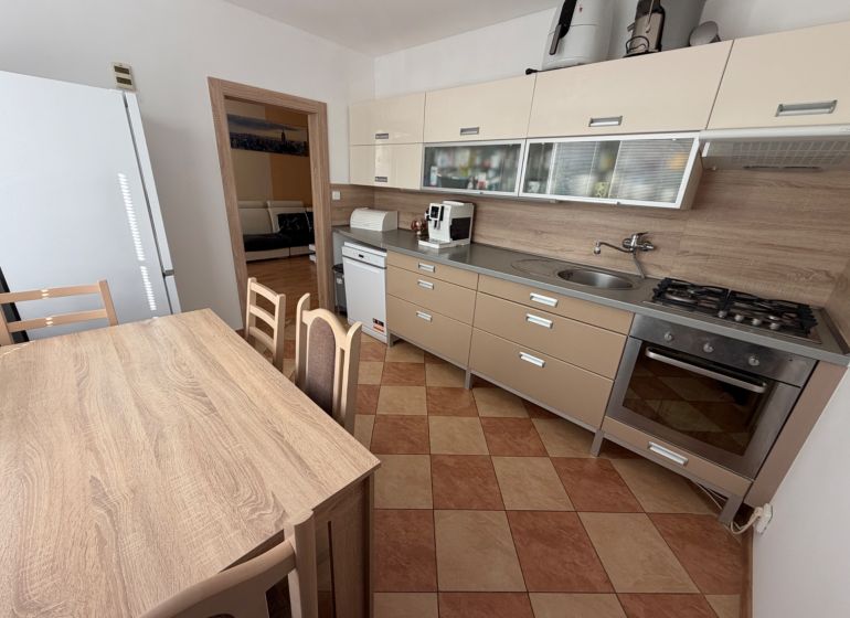 Küche einer 3-Zimmer-Wohnung mit Eckküche, Esstisch und Geräten.