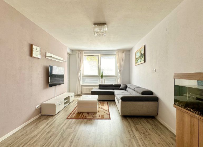 Wohnzimmer in einer 3-Zimmer-Wohnung mit Ecksofa und Boden in Holzoptik.